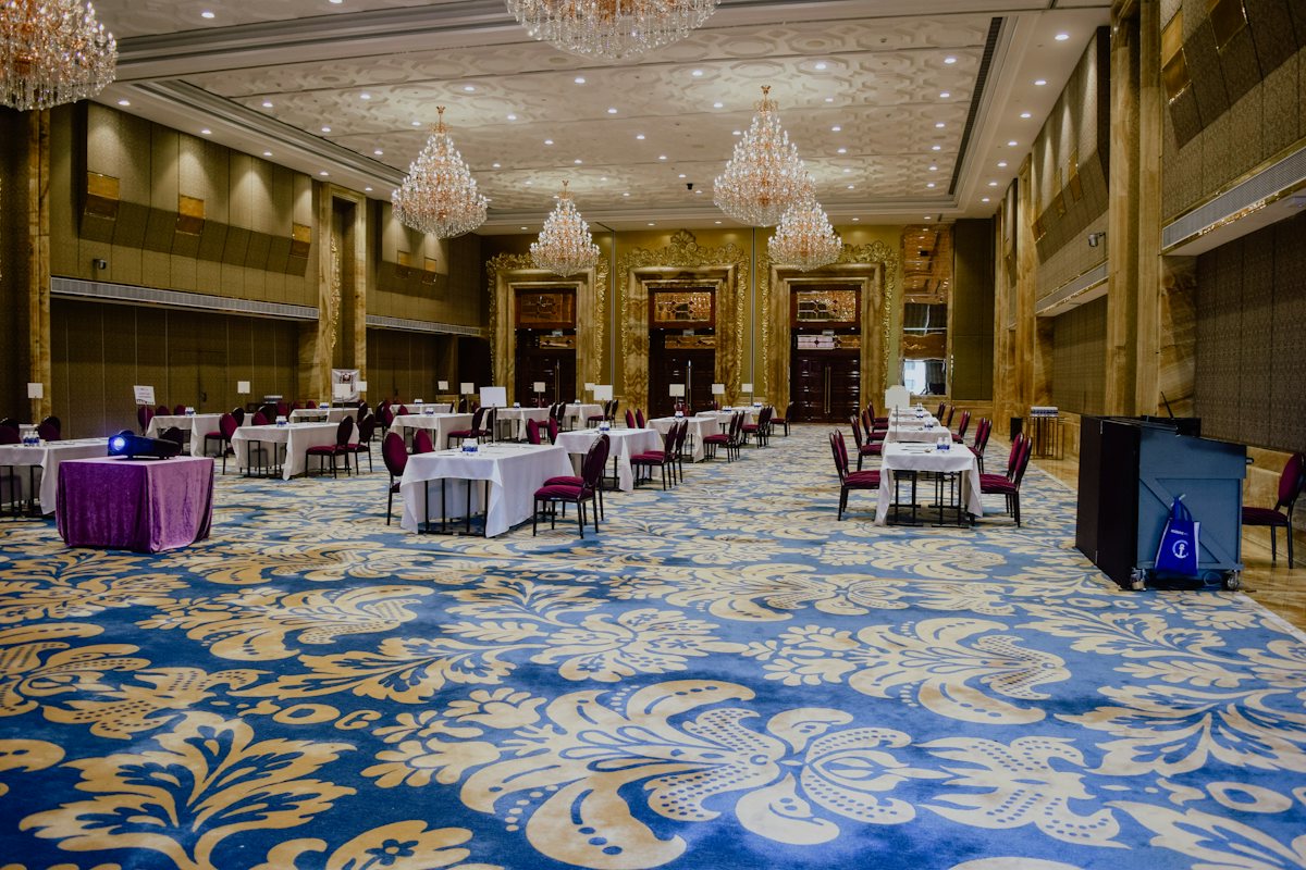 Salón de eventos preparado con mesas y alfombra limpia